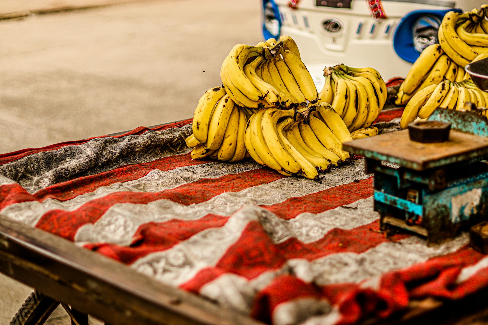 Ripe bananas displayed on a market cart with scales, ready for sale.