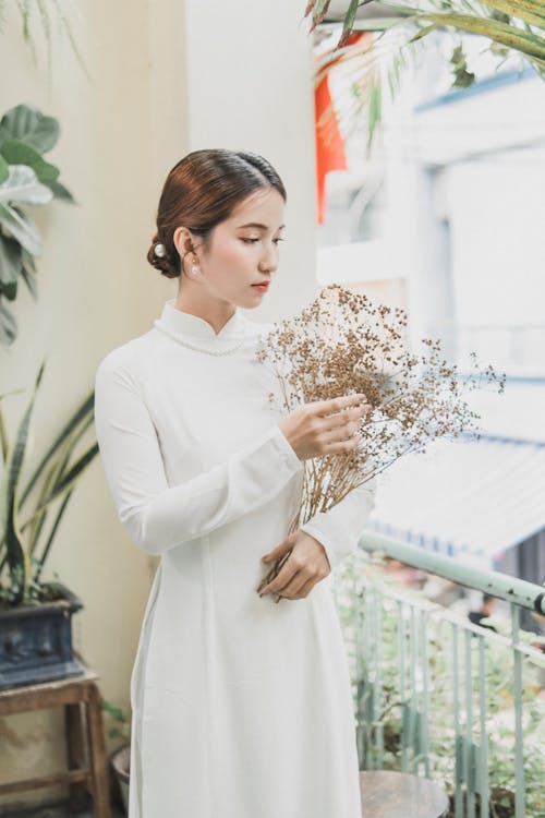 Free A Woman in a White Dress Holding Dry Flowers Stock Photo