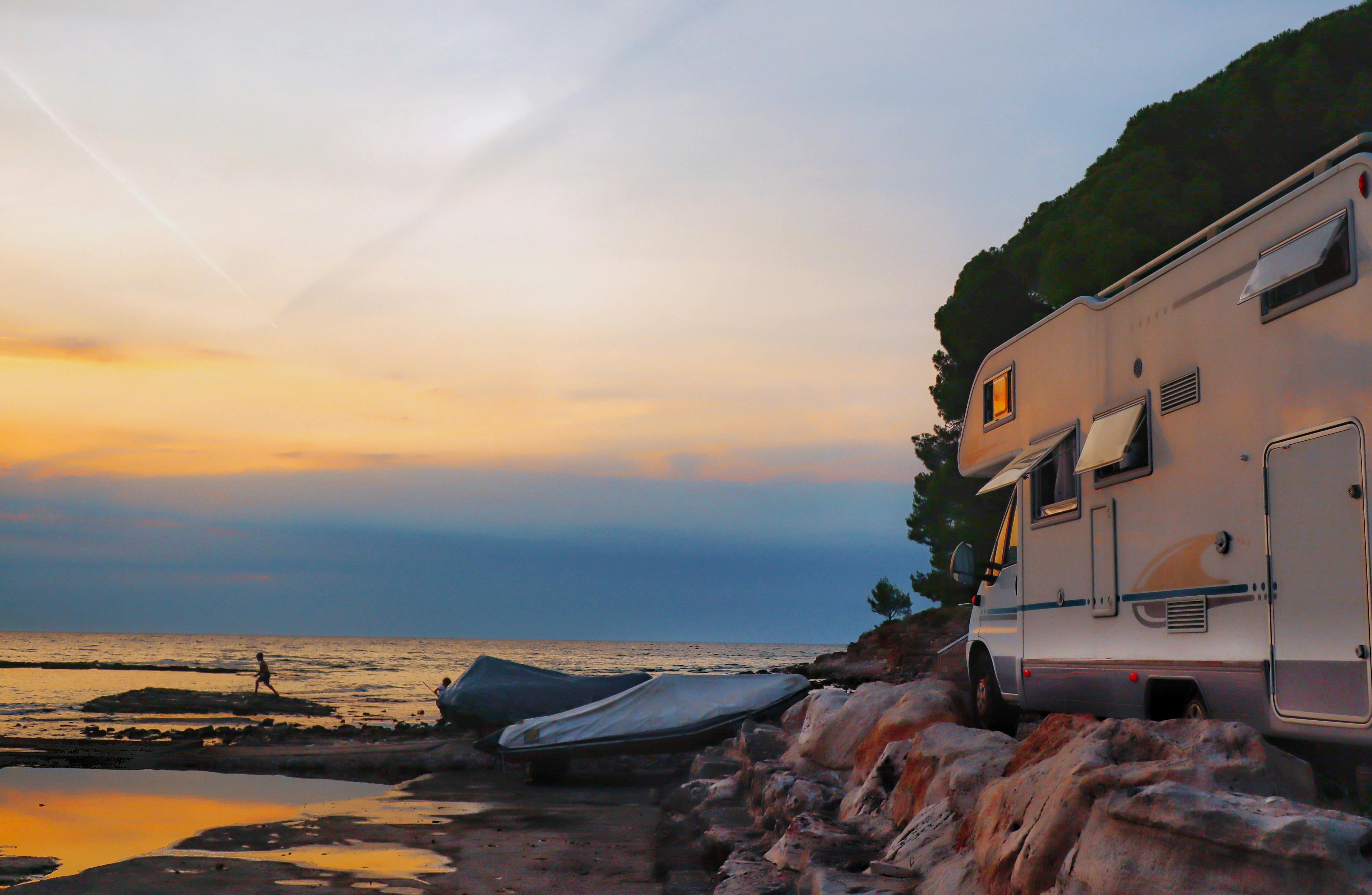 Explore a serene coastal escape with an RV parked by the seaside at sunrise, perfect for a travel getaway.