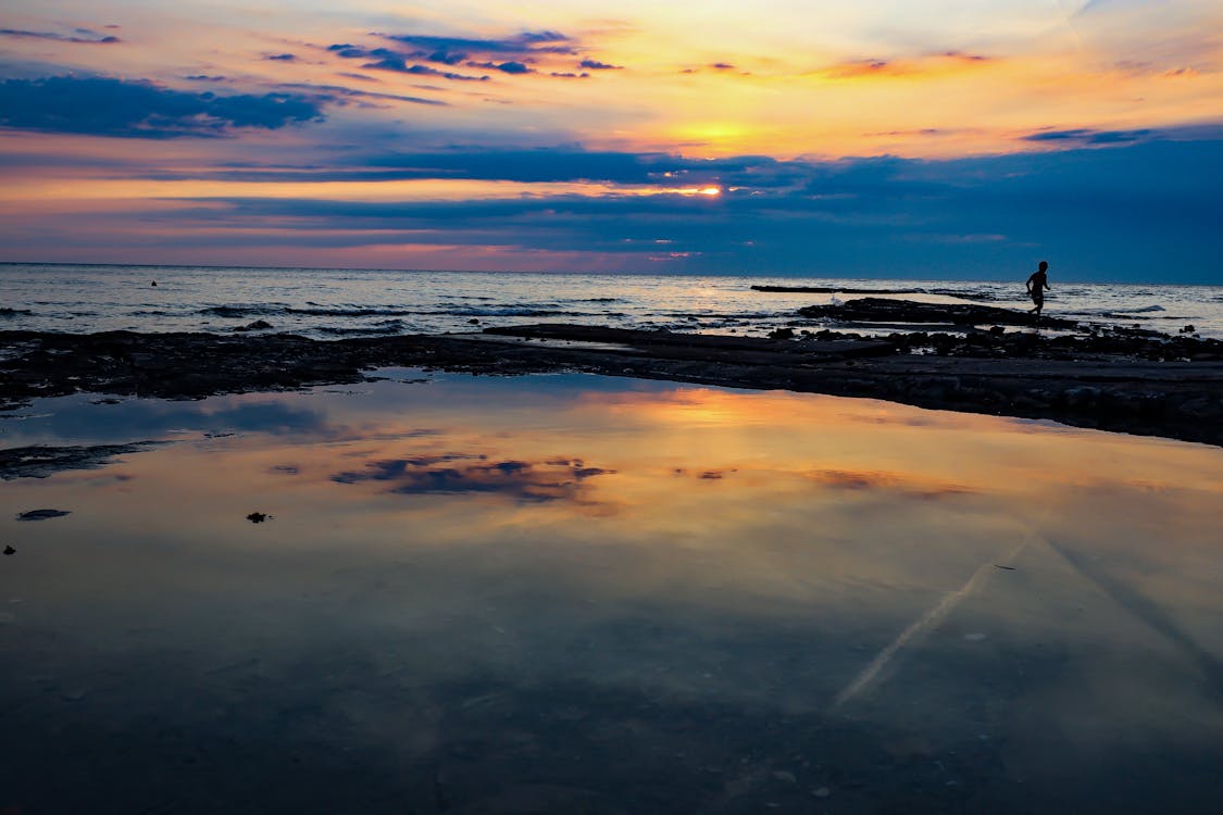 A Body of Water Under Sunset Sky 