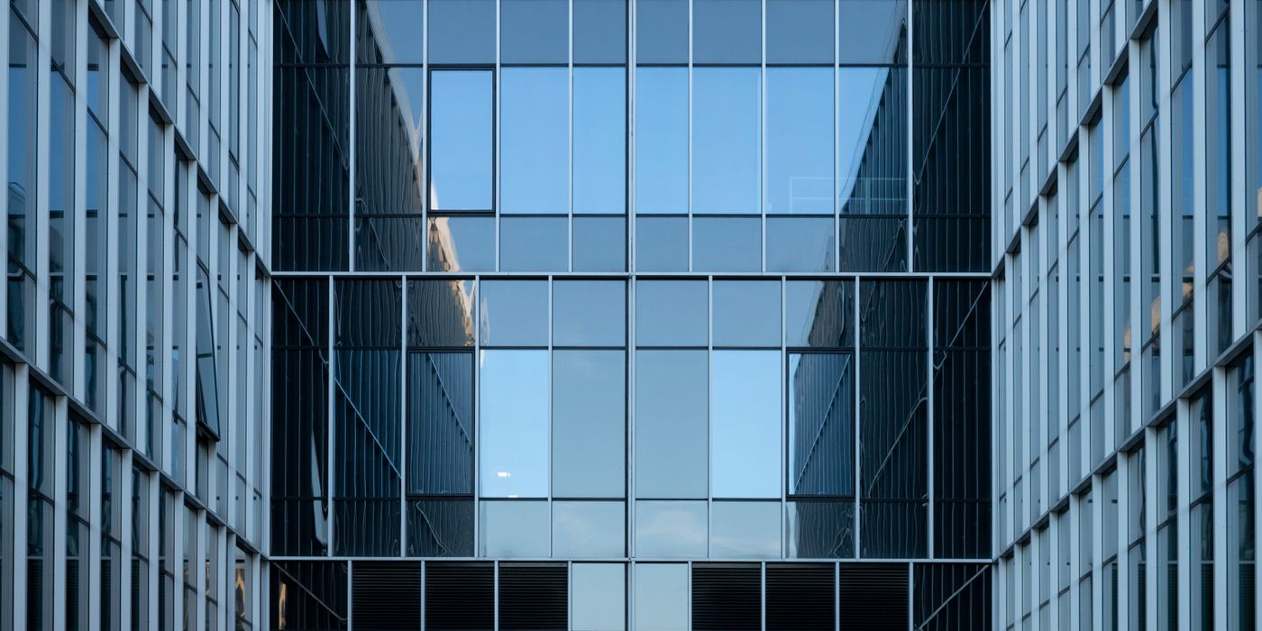Contemporary building facade with reflective glass windows in an urban environment.