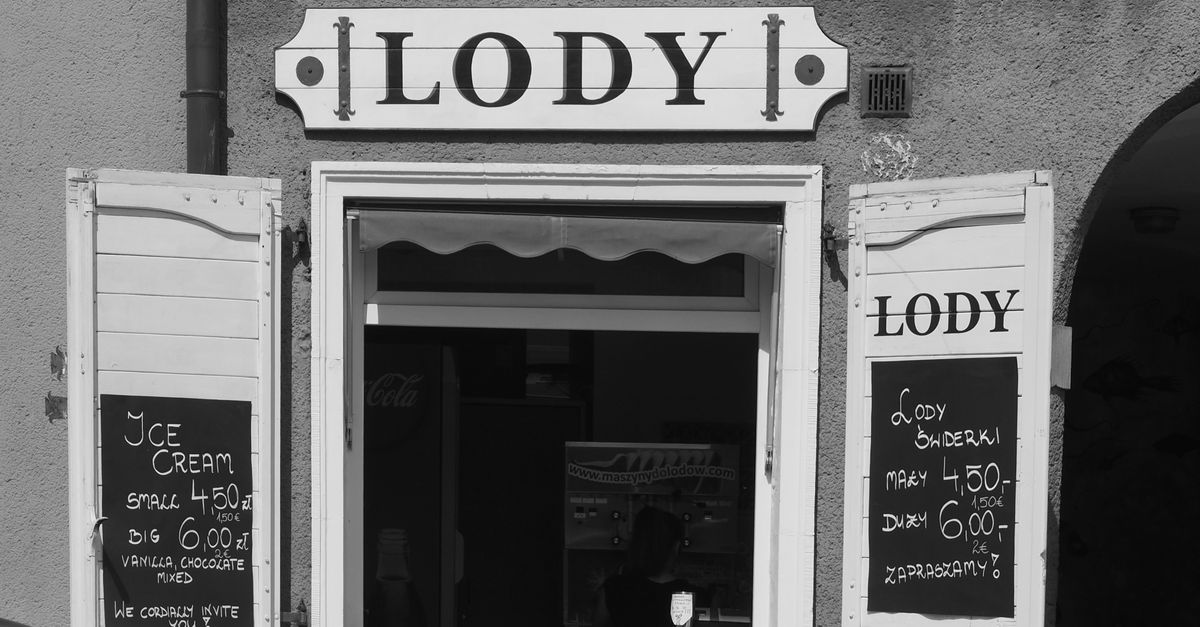 Black and white image of a classic ice cream shop in Gdańsk, Poland, featuring vintage signage.