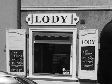 Black and white image of a classic ice cream shop in Gdańsk, Poland, featuring vintage signage.