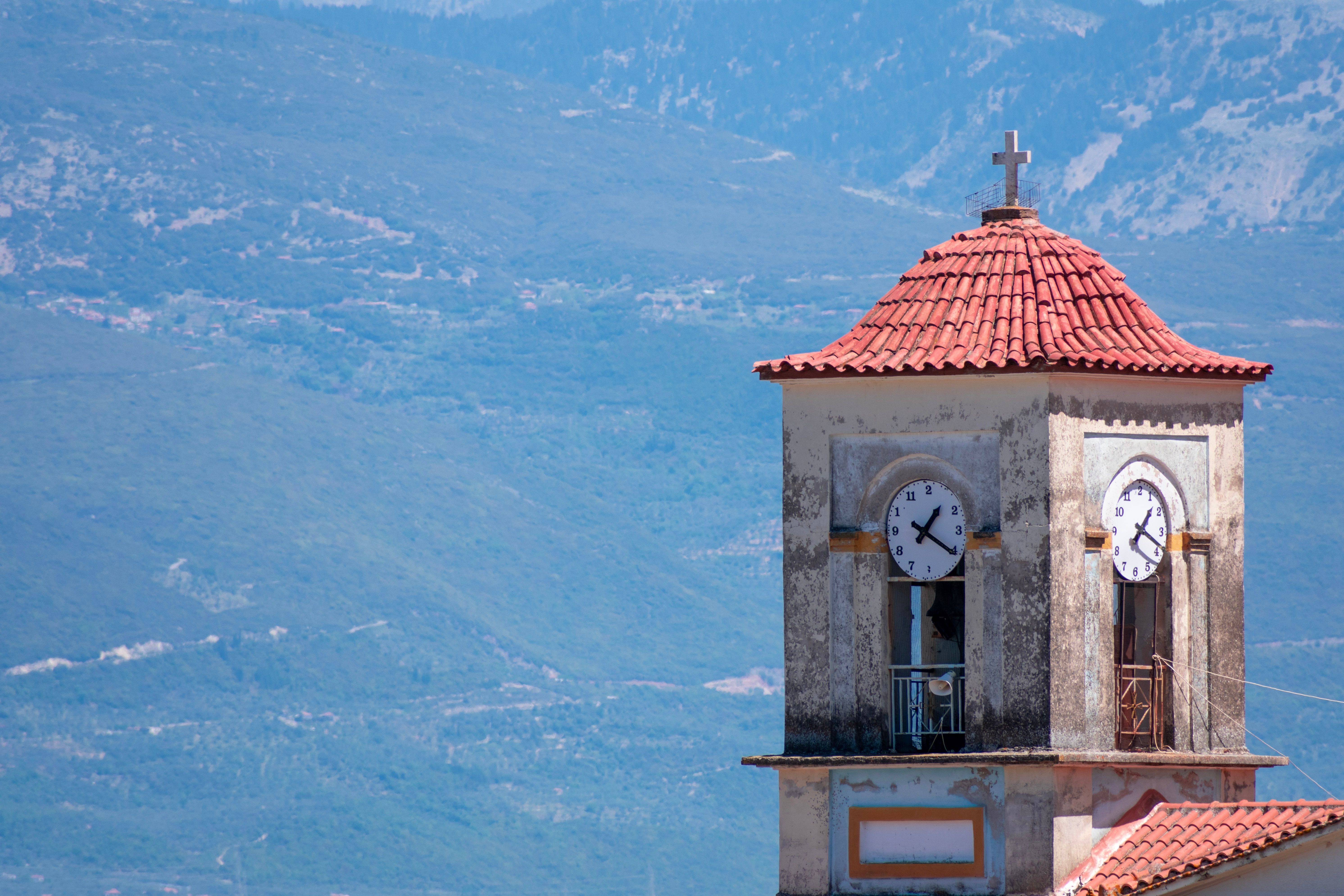 Rustic church clock tower against mountainous landscape in Agrinio, Greece.