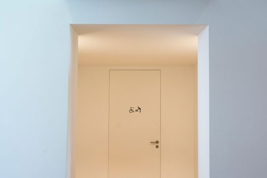 A clean and minimalist indoor space featuring an accessible restroom sign on a closed door.