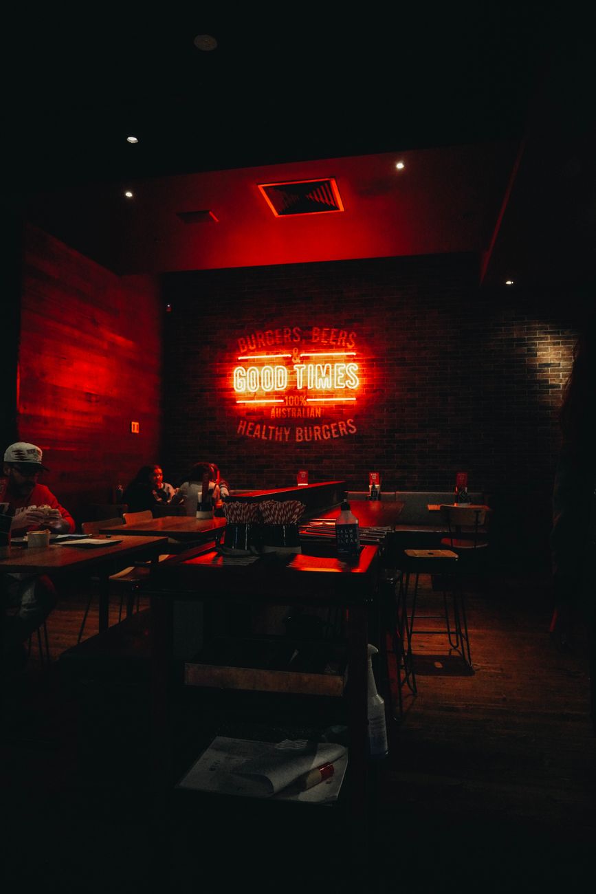 A moody Melbourne restaurant interior with low tables, warm lights and a neon accent