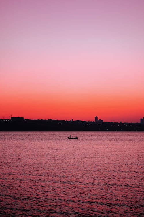 Pink River and Red Horizon with Silhouette Boat at Dusk