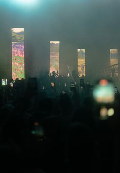 A dynamic concert atmosphere in İstanbul with smartphones capturing the action.