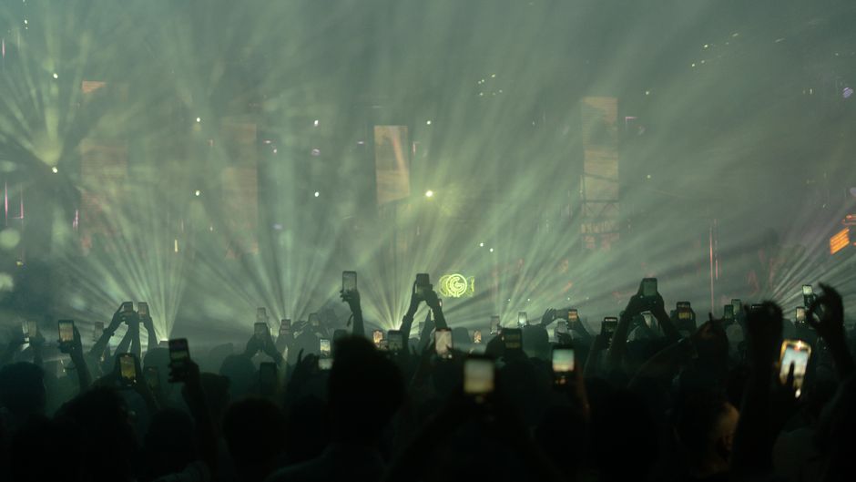 Dynamic crowd at a night music festival in Istanbul with bright stage lights.