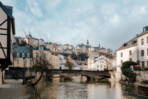 Free Picturesque view of a historic European town with a central river and bridge under a cloudy sky. Stock Photo