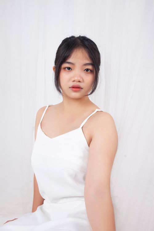 Free Stylish portrait of a woman in a white dress with a bright background, showcasing elegance and simplicity. Stock Photo