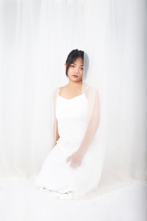 Girl in White Dress Near Curtain 