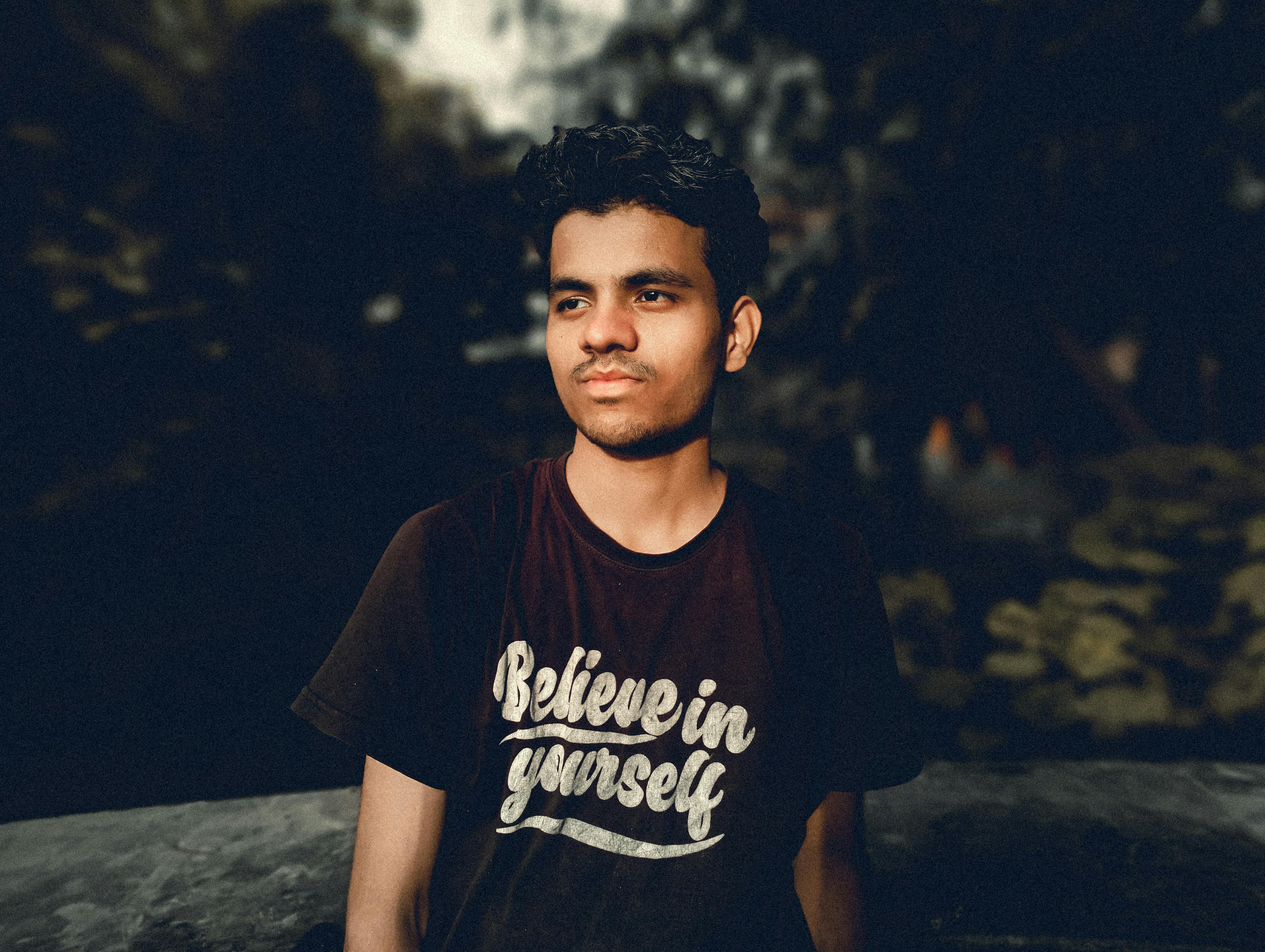Close-up outdoor portrait of a young man in a printed crew neck t-shirt with motivational text.