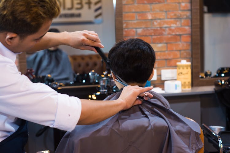 Barber Cutting Client Hair In Saloon