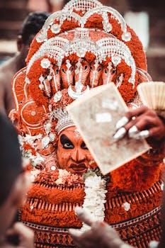 Close-up of a Theyyam performer in vibrant traditional costume during a cultural festival in Kannur, India.