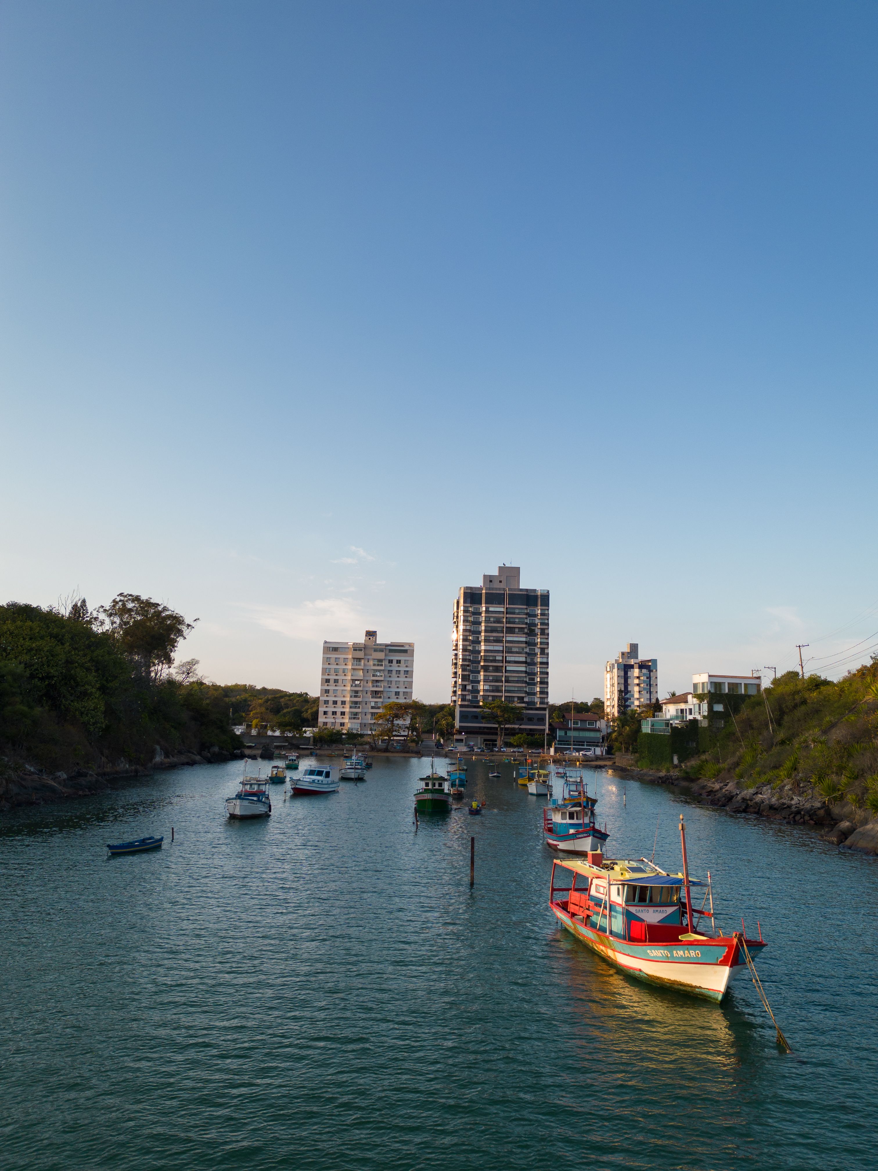 Colorful boats docked at the Praia da Costa canal with buildings in the backdrop.