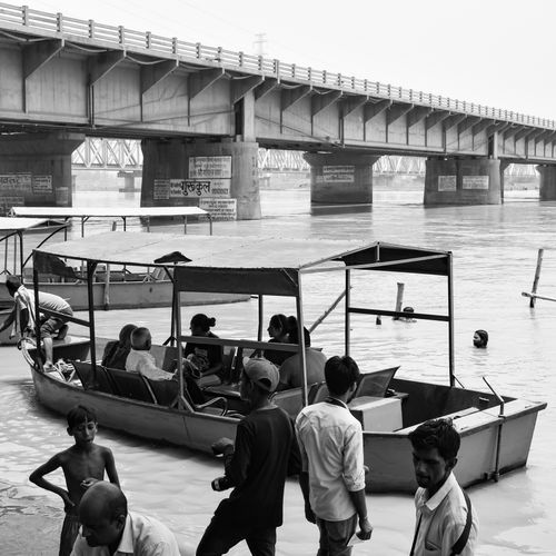 Free People gather on a boat by a bridge in India in this black and white photo. Stock Photo