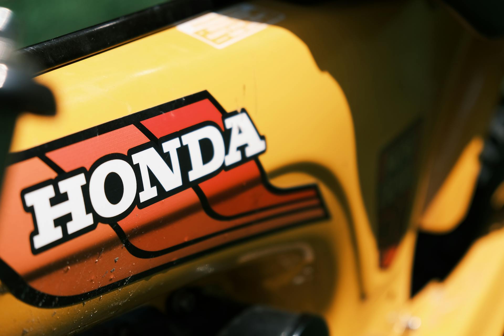 A detailed image of a vintage yellow Honda logo on a vehicle, showcasing iconic branding.