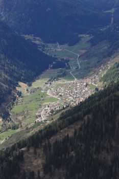 Stunning aerial view of an alpine village nestled in a verdant valley surrounded by lush mountains.