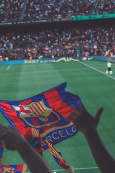 Fans waving flags during a vibrant soccer match at a stadium in Barcelona.