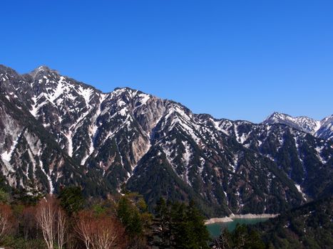 Majestic snowy mountains under a clear blue sky in Kurobe, Japan, showcasing nature's beauty.