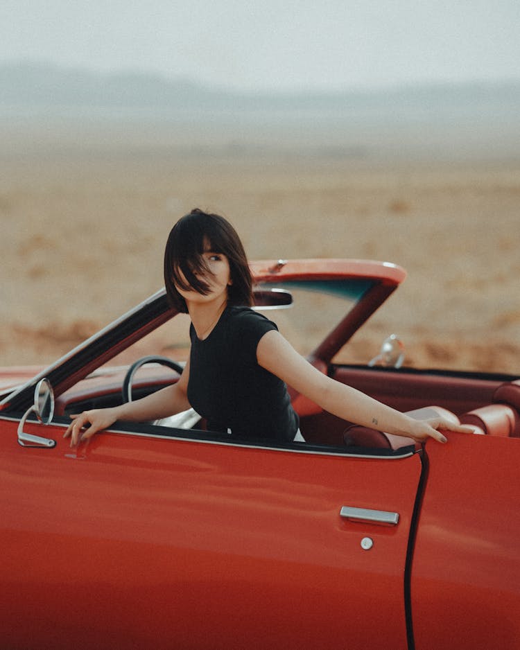 Young Woman In A Red Cabriolet Looking Back 