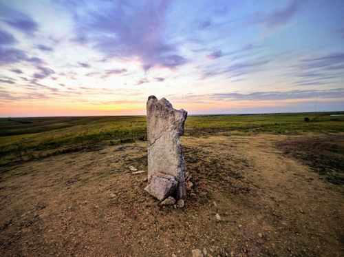 Free Sunset over a Kansas field with a prominent stone monolith, capturing rural beauty and tranquility. Stock Photo