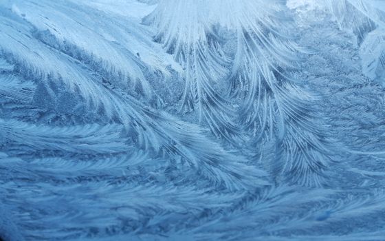 Close-up of delicate frost patterns capturing the essence of winter's chill on a window surface.