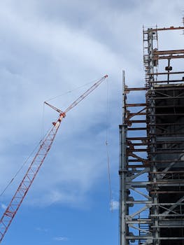 Tower crane at construction site in Bangladesh, displaying steel structure against clear blue sky.
