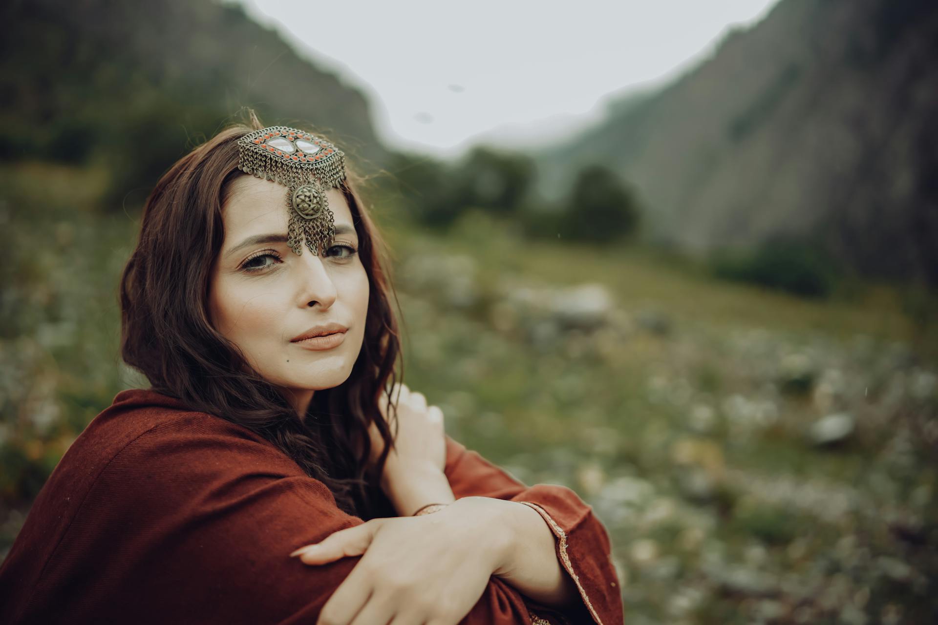 Foto van een vrouw in een Afghaanse Kuchi-stamhoofdhalsband die in de natuur zit