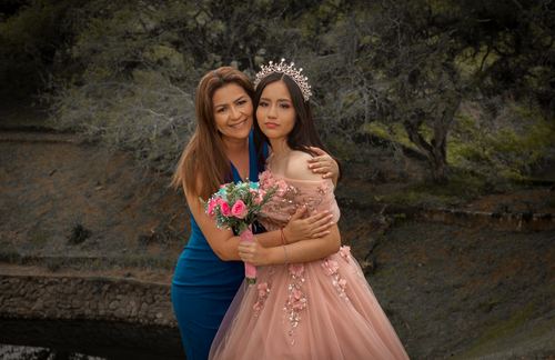 Free A woman in blue hugs her daughter in a crown and gown, celebrating in nature. Stock Photo