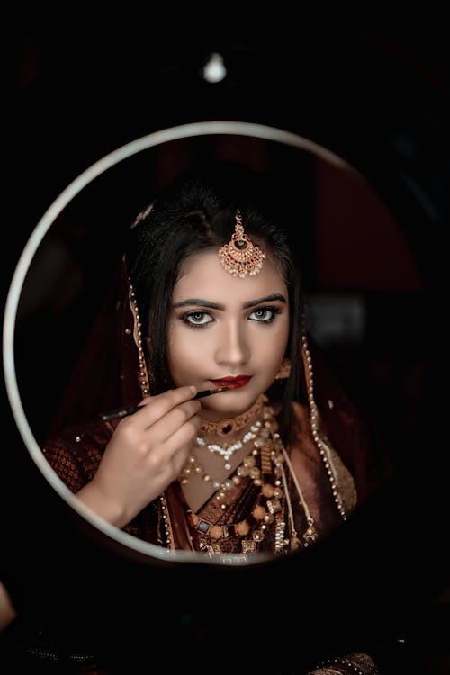 Young Woman Wearing Traditional Jewelry Doing Her Makeup 