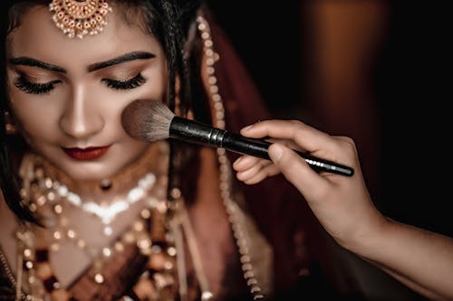 Photo of a Woman in a Traditional Clothing Having her Makeup Done 