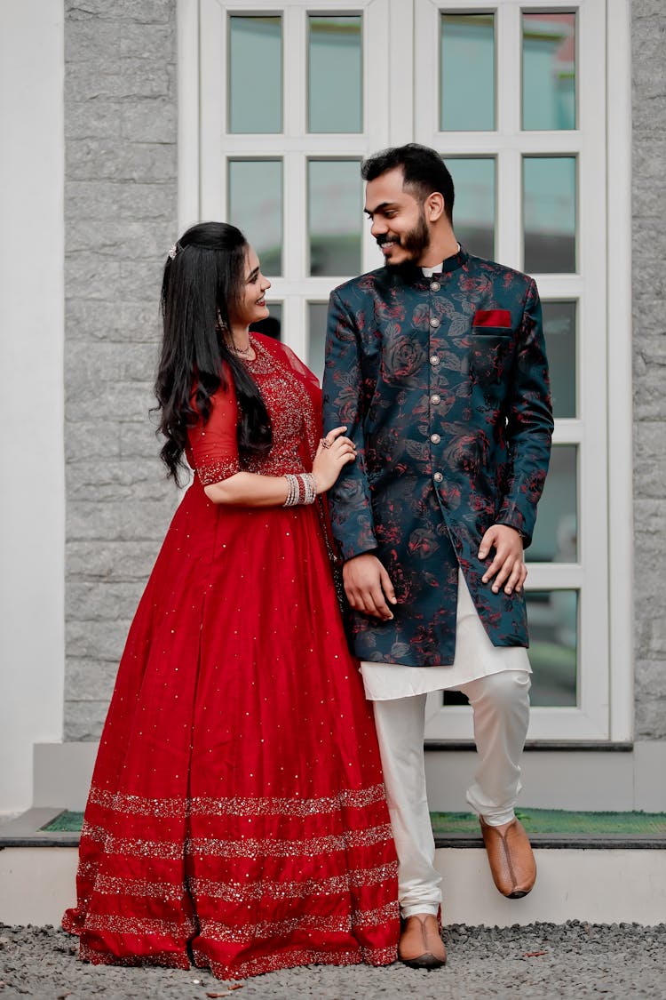 Man And Woman Posing In Traditional Silk Clothing Against A Window