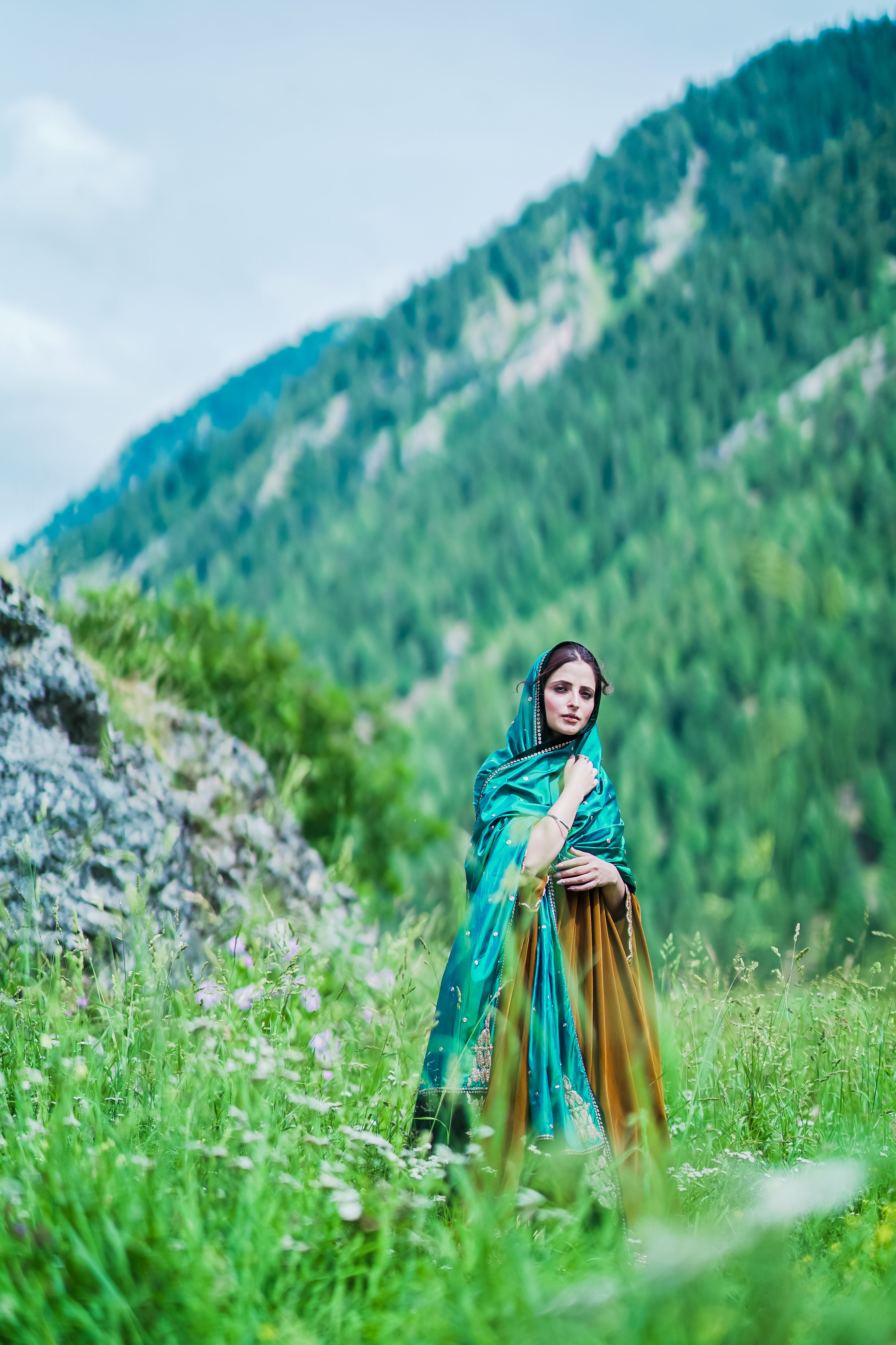 [ColoSach]-woman-in-colorful-attire-standing-in-lush-green-mountainside,-evoking-a-serene,-natural-setting.