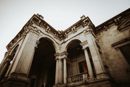 Free Low angle view of a historical stone building with arches and columns, emphasizing classical architecture. Stock Photo