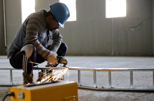 Man Using Angle Grinder on Ladder