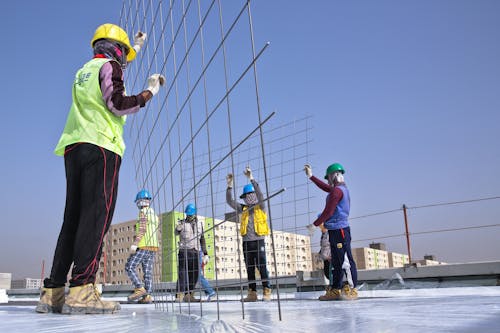 Unrecognizable builders installing grid construction on roof of building