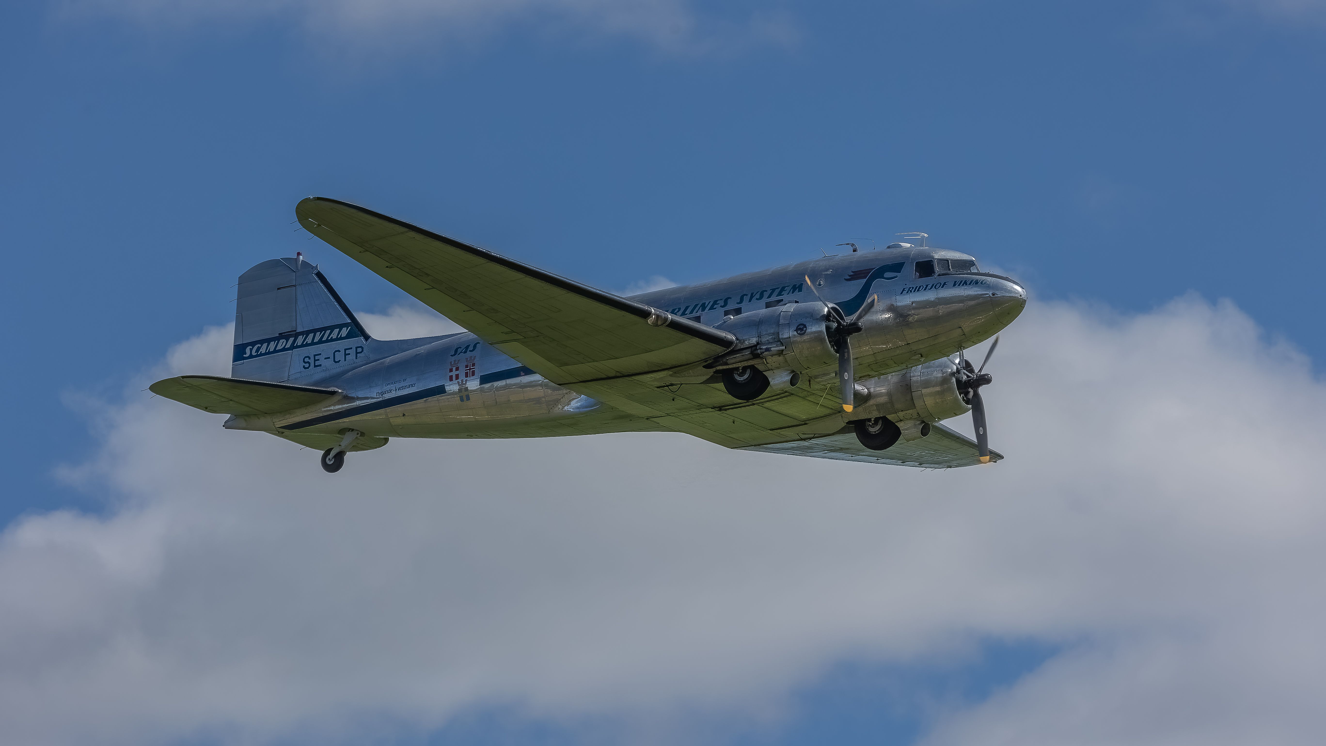 A classic propeller aircraft soaring through a clear blue sky, showcasing its vintage design.