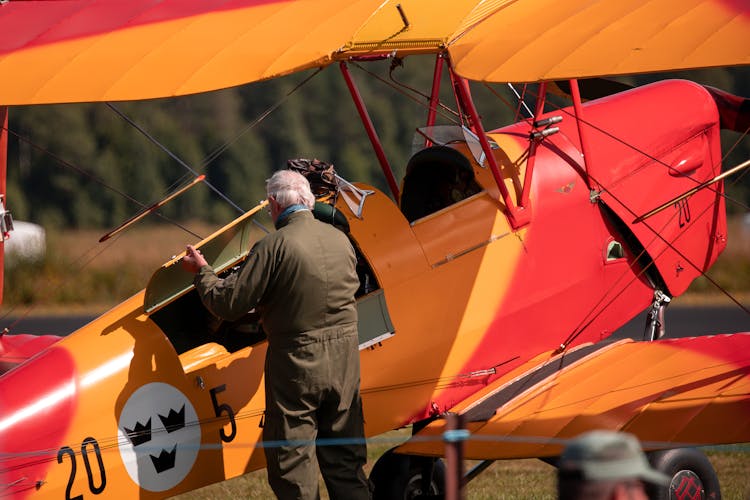 Man Standing Beside An Orange Airplane