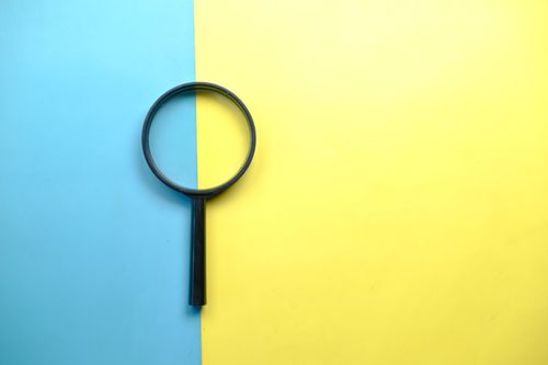 Magnifying glass on a split blue and yellow background — photo by Towfiqu barbhuiya on Pexels
