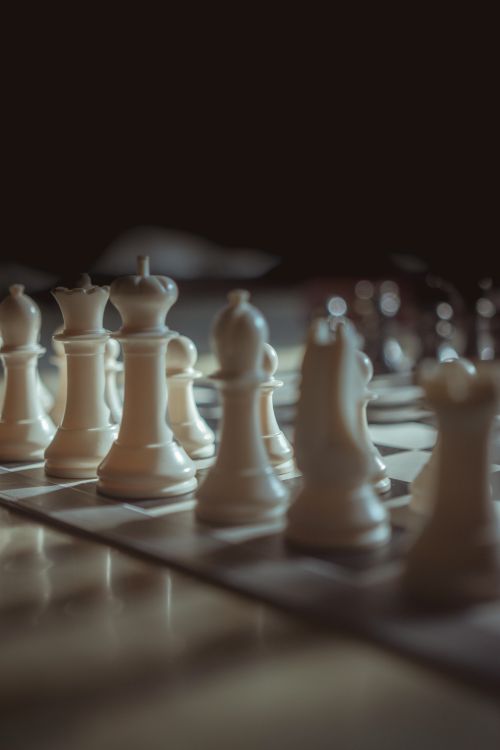 Free Artistic close-up of white chess pieces on a chessboard, creating a moody atmosphere. Stock Photo
