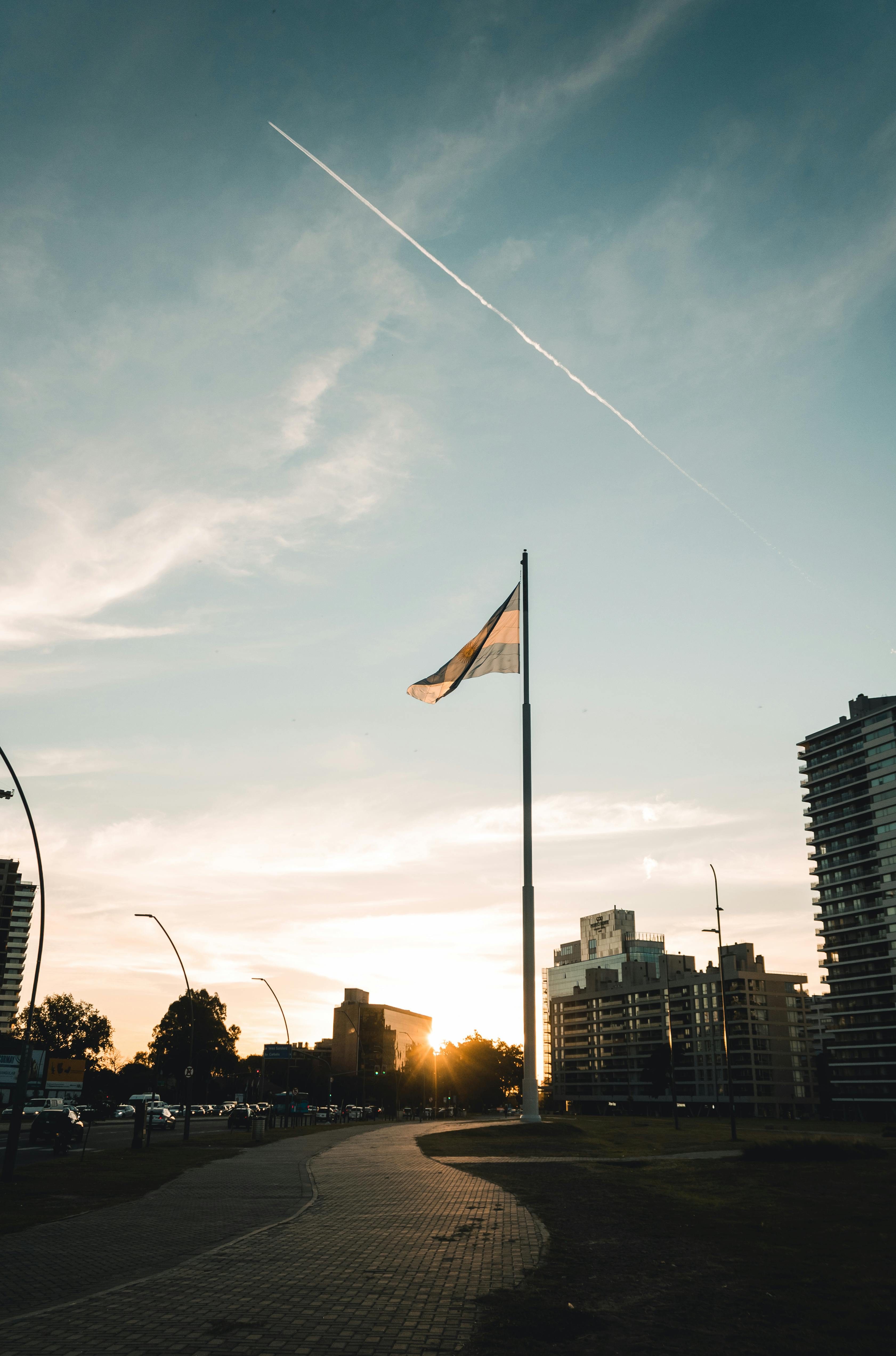 Dramatic sunset skyline of Rosario, Argentina, with the national flag waving prominently.