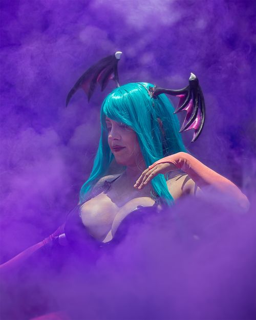 Free A woman in elaborate cosplay and teal wig amidst a vibrant purple smoke backdrop. Stock Photo
