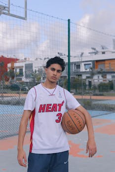 A confident young athlete stands on a basketball court in Casablanca, holding a ball