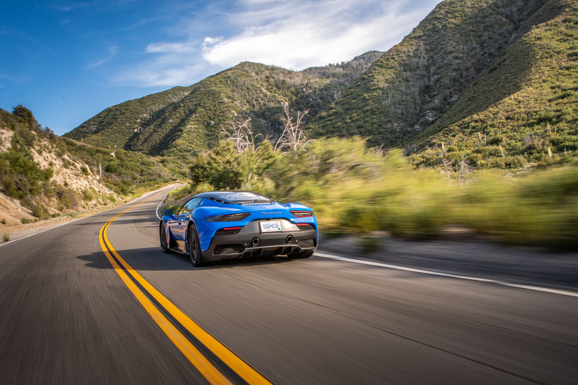 Exotic sports car navigating scenic winding canyon road above Los Angeles at sunset