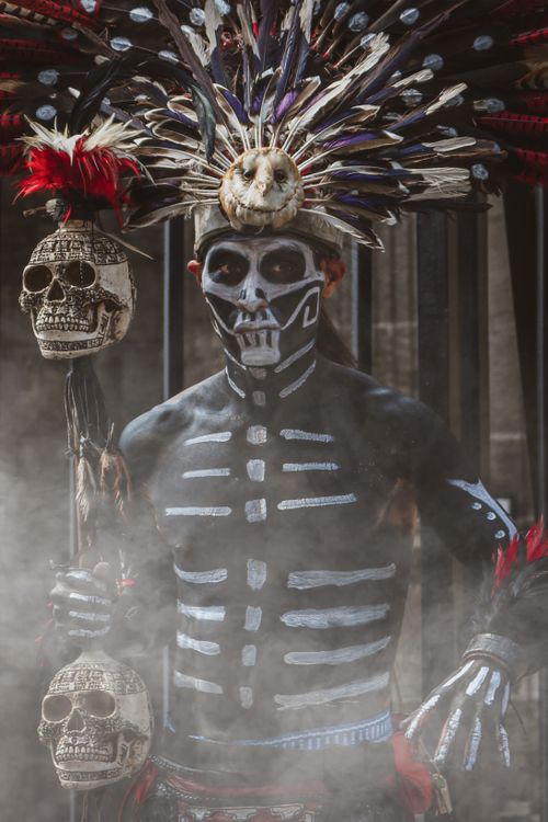 Free A man in tribal costume with skull face paint and headdress, exuding a mysterious and haunting presence. Stock Photo