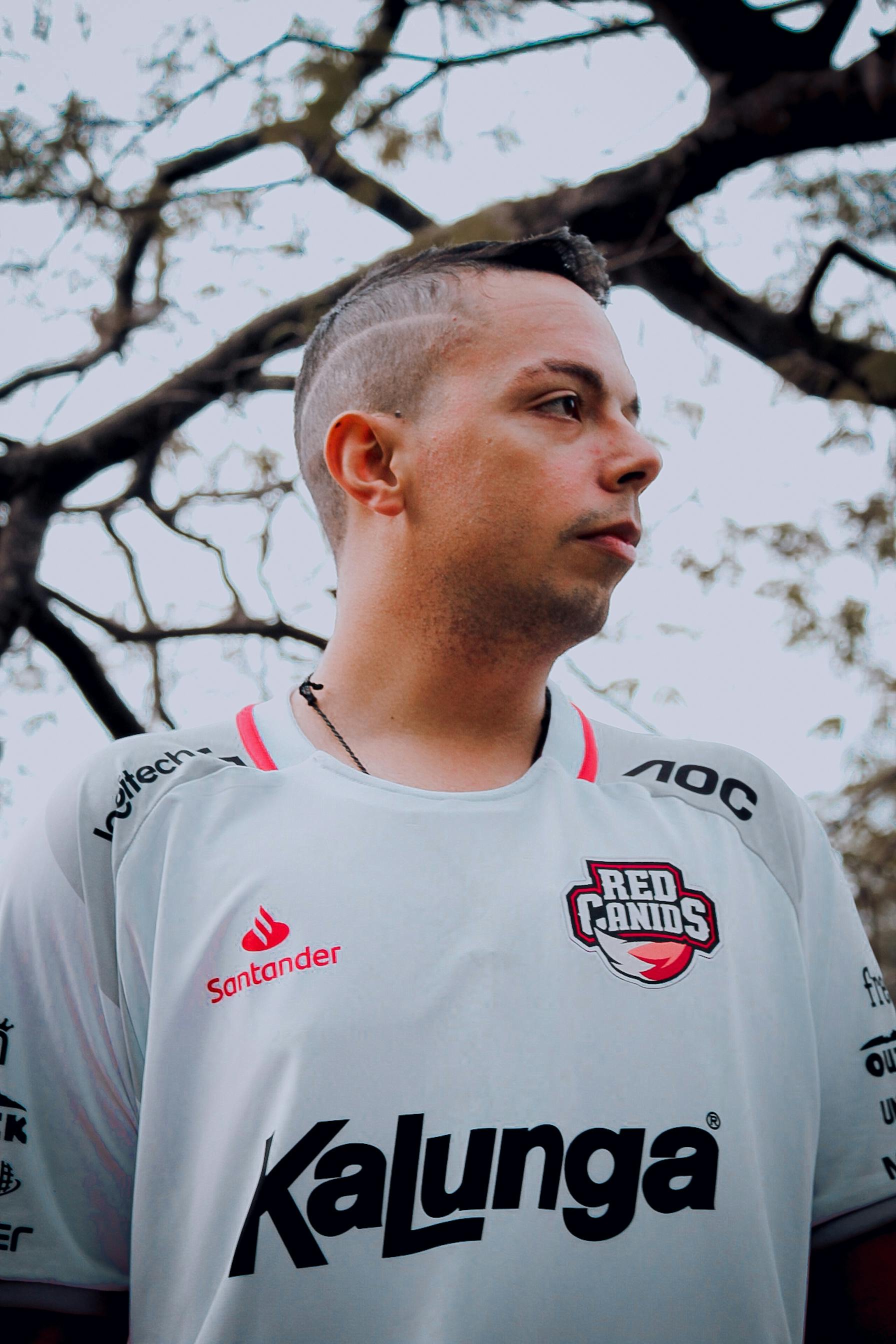 Young man in sports jersey outdoors, confident and stylish profile view.