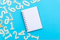 在充满活力的蓝色背景上，顶视图的空白笔记本电脑旁散落着数字