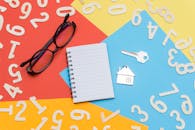 桌面上散落着彩色的扁平物品，包括笔记本、眼镜和几把房屋钥匙